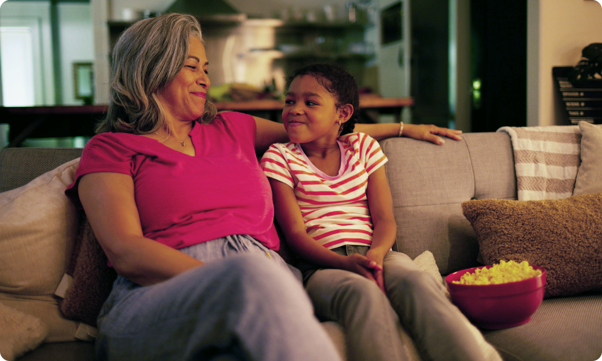 Potential OPDIVO® (nivolumab) user watching a movie on the couch with her granddaughter.